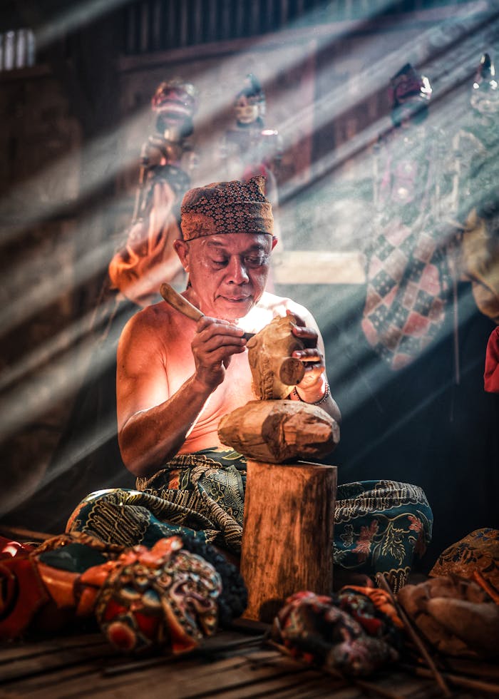 A skilled artisan in West Java intricately carves a traditional Javanese wooden puppet.